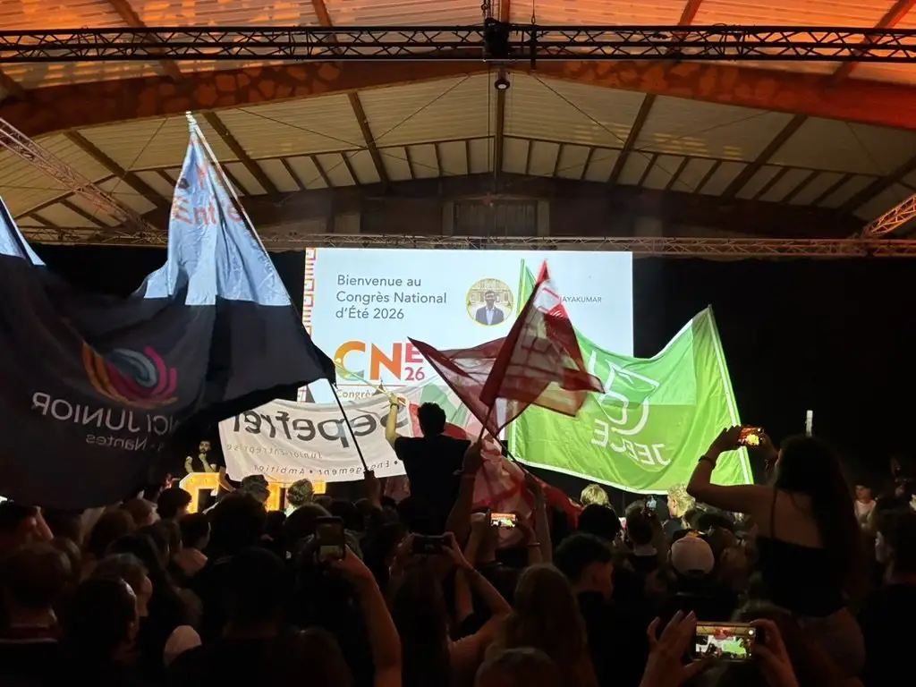 Plenary room of the National Summer Congress: Junior Enterprise flags waving in front of the welcome screen.