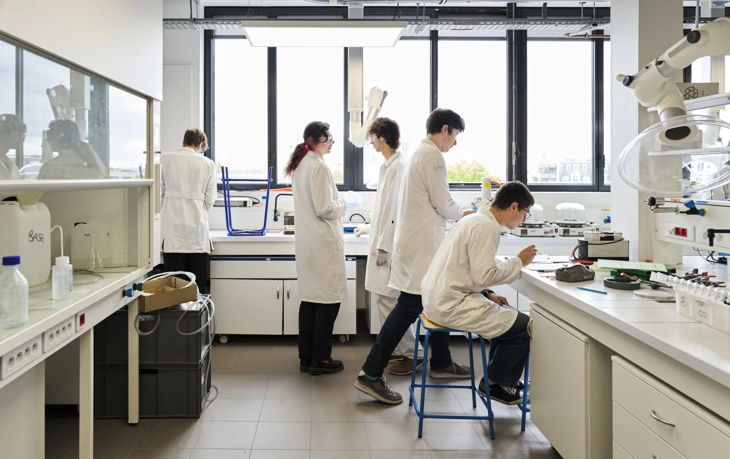 Engineering students in lab coats working in an ESPCI chemistry laboratory.